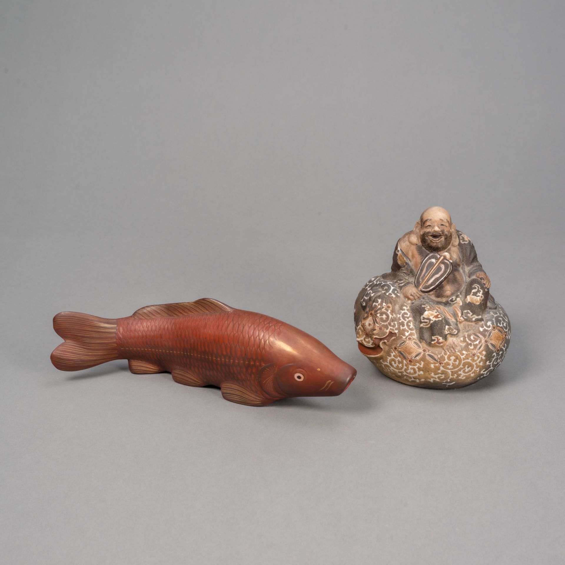 A BIZEN WARE FIGURE OF HOTEI SEATED ATOP HIS BAG AND A RED-AND GILT -LACQUERED WOOD OKIMONO OF A CA