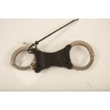 A set of stainless steel and black plastic Hiatt rigid handcuffs; 22cm long; (complete with key)