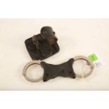 A set of stainless steel and and black plastic Hiatt rigid handcuffs with black leather holster #