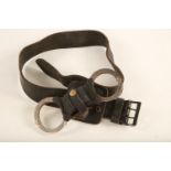 A set of stainless steel and and black plastic Hiatt rigid handcuffs with black leather holster on a