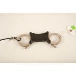 A set of stainless steel and black plastic Hiatt rigid handcuffs; 22cm long; (complete with key)