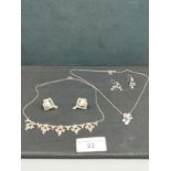 2 silver necklaces with ornate designs together with 2 sets of silver earrings .