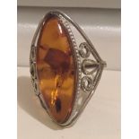 White metal ring with amber style stone .