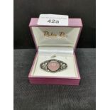 Sterling silver ornate brooch with pink stone and maracite setting .