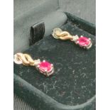 Pair of 14kt gold earrings set with diamond and ruby stones .