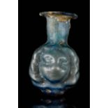 A ROMAN PALE GREEN GLASS JANUS-HEAD SPRINKLER FLASK