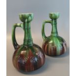 A pair of Art Nouveau design pottery single handled onion shaped green and brown glazed vases.