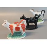 Two Staffordshire pottery cow creamers, together with a Staffordshire reproduction cow creamer. (