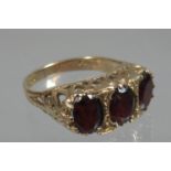9ct gold three stone garnet dress ring. Ring size O. Approx weight 3.8 grams. (B.P. 21% + VAT)