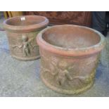 Pair of weathered terracotta planters of circular form with moulded decoration of cherubs to the