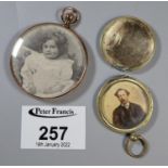 A 9ct gold Edwardian photograph locket and a yellow metal photograph locket with engraved cover. (