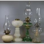 Three early 20th century single oil burner oil lamps with clear moulded and opaline glass reservoirs