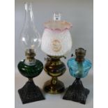 Two early 20th century single burner oil lamps with coloured reservoirs, on cast metal bases.