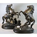 Pair of early 20th century spelter Marley horses and figures on oval naturalistic base. (2) (B.P.