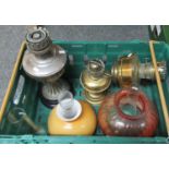 Box with two brass oil lamp bodies, one ornate metal oil lamp body, three glass chimneys, a pink
