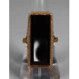 Yellow metal dress ring set with a large rectangular onyx stone. Ring size O. Approx weight 6 grams.