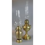 Two early 20th Century single oil burner lamps with clear glass chimneys, both on a brass