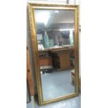 Modern gilt framed mirror of rectangular form carved with flowers. 62 x 133cm approx. (B.P. 21% +