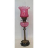 Early 20th century double oil burner lamp with cranberry shade, cranberry reservoir standing on a