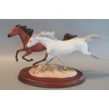 Franklin Mint fine porcelain group of two galloping horses, one dapple grey on naturalistic rockwork