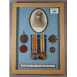 Framed and glazed WWI medal duo together with photograph, dog tags, cap badge, and enamelled