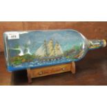Vintage glass ship in a bottle, the wooden base marked 'The Joiner'. (B.P. 21% + VAT)