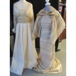 Two striking wedding dresses in champagne and deep cream, one with a, probably silk, pleated skirt