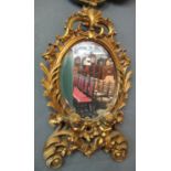 Modern gilt framed oval bevelled hanging mirror decorated with scroll work and cherubs, bevel the