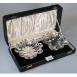 Cased pair of silver sweet meat dishes with scalloped edges and pierced decoration, both standing on