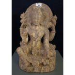 Stone statue of a seated Shiva, here depicted with four arms, the raised left holding a small