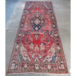 Red ground Iranian runner with multi coloured floral medallion. 305 x 118cm approximately. (B.P. 21%