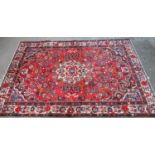 Persian suruk full pile hand woven rug on a red ground with central medallion surrounded by flowers,