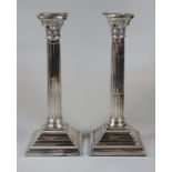 Pair of silver Corinthian column candle sticks of typical form, standing on square stepped and