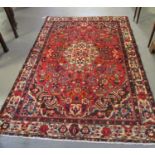 Persian suruk full pile hand woven rug on a red ground with central medallion surrounded by flowers,