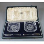 Cased set of two glass square butter dishes with two silver butter knives, the box labeled