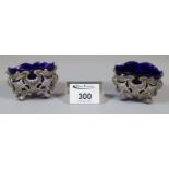 A pair of pierced and repousse decorated silver salts with blue glass liners. Approx silver weight