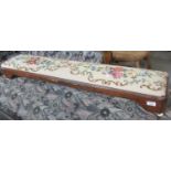 A Victorian walnut tapestry footstool of low rectangular form raised on ceramic fluted feet. 122cm