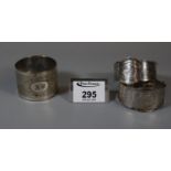 Pair of white metal napkin rings marked H & M, together with another engine turned napkin ring. (