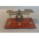 Set of brass postal scales with some weights on rectangular wooden base. 18cm wide approx. (B.P. 21%