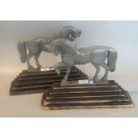 Pair of white metal andirons/door stops in the form of horses on ebonised stepped wooden bases. 54cm