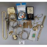 A collection of vintage costume jewellery in a tin including an, ?Aseikon? manual pendant watch. (