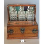 Early 20th century oak metal mounted three bottle tantalus having lidded compartments for cigars and