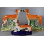 Three 19th century Staffordshire figures of dogs to include: a recumbent greyhound on a blue ceramic