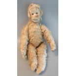 Early 20th century straw filled mohair monkey with glass eyes and movable limbs, the label marked
