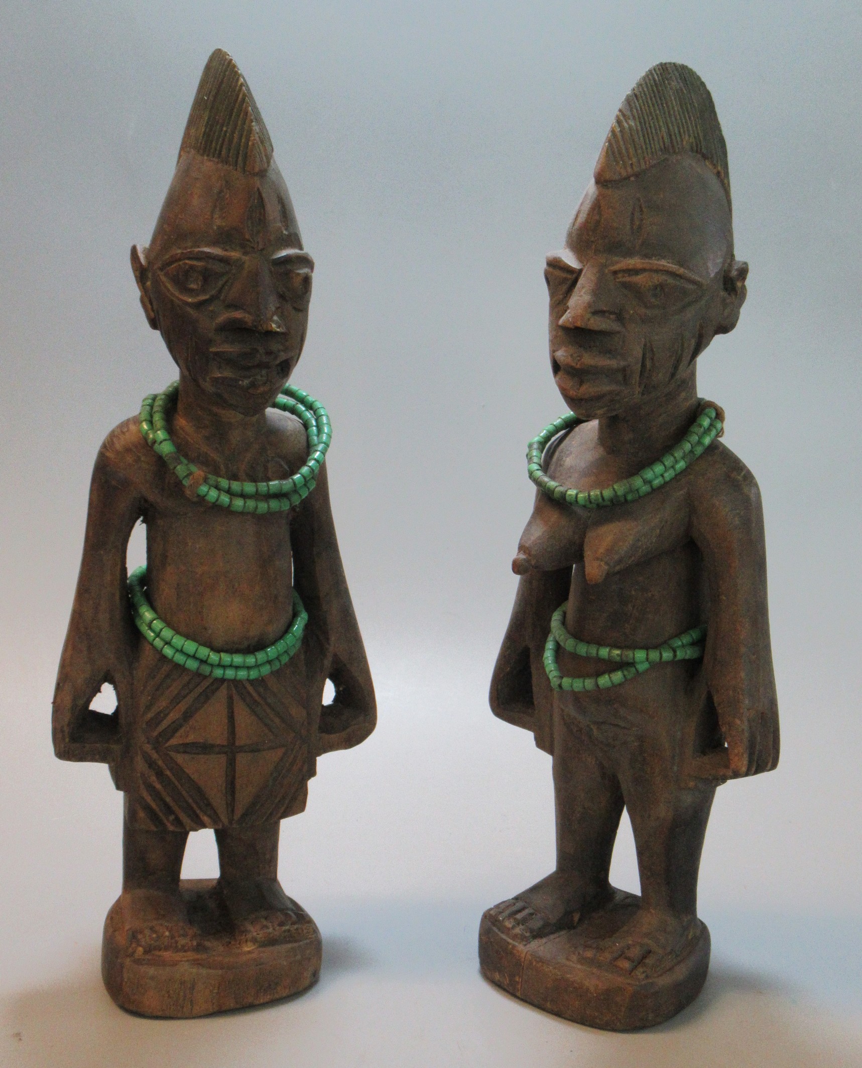 Pair of African carved wooden tribal figures of a man and nude woman decorated with green beads 28cm
