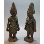 Pair of African carved wooden tribal figures of a man and nude woman decorated with green beads 28cm