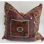 Large woven cushion in traditional geometric patterns with muted colours of claret, blue, brown,