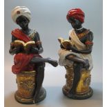 A pair of modern Blackamoor bronzed and painted Arabian seated figures reading books on gilded
