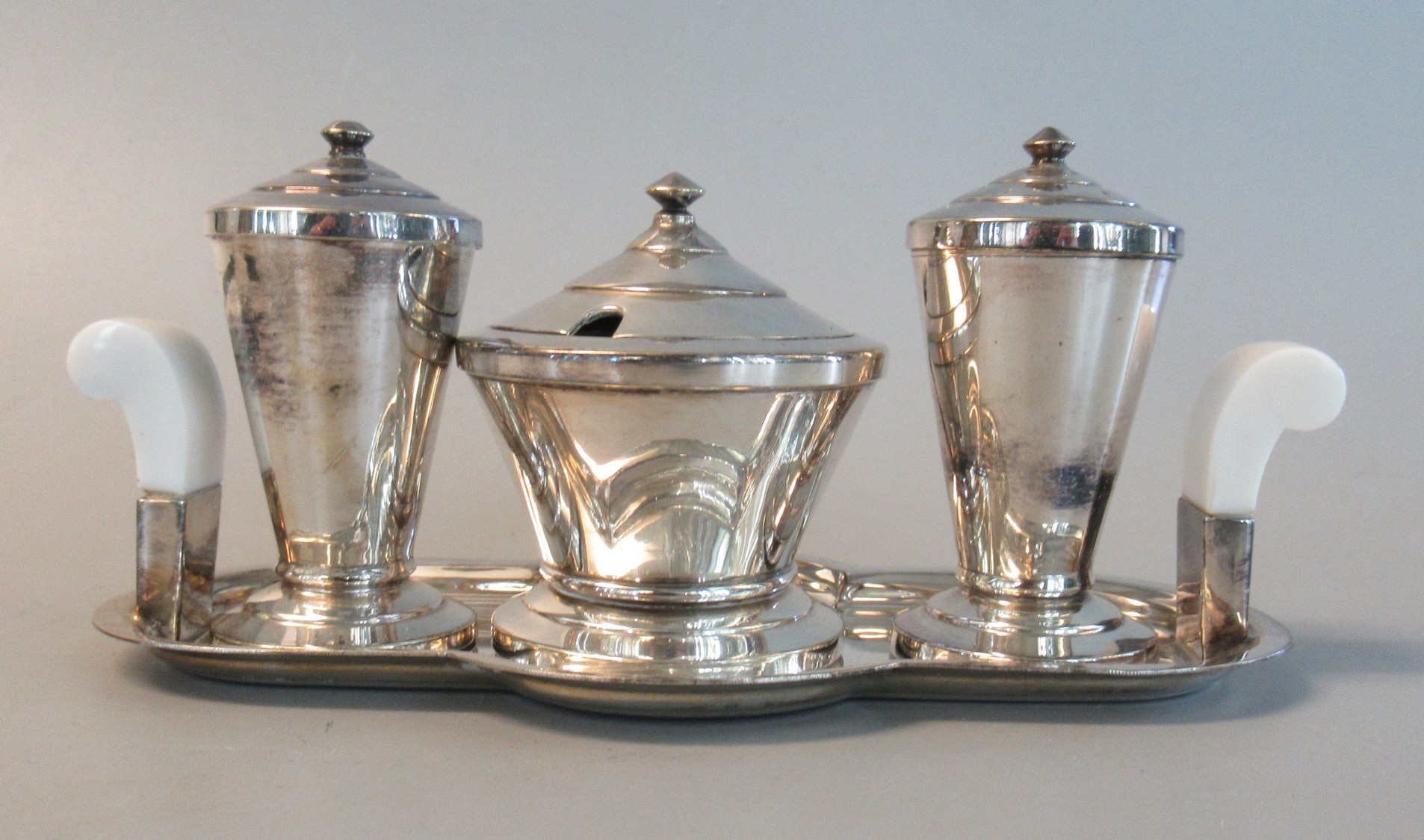 An Art Deco silver plated 3 piece cruet set with white bakelite handles on stand. (B.P. 21% + VAT)