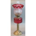 Early 20th century double oil burner lamp having cranberry and clear glass shade above a cranberry